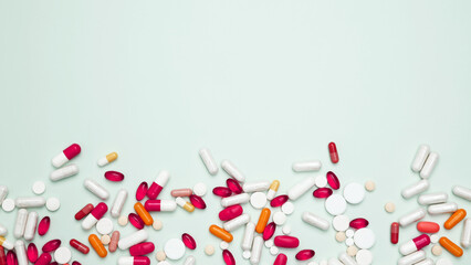 Various colorful pills and capsules scattered on a light blue background. Concept of medicine, healthcare, and pharmaceutical industry