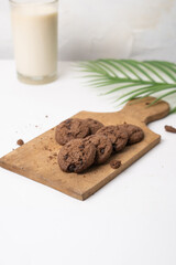tasty chocolate cookies with glass of milk on wooden tray
