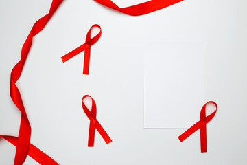 Red ribbon with awareness about AIDS on a white background and paper for mock up. World AIDS Day