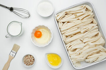 Filo dough in a baking dish near milk, eggs, butter, butter, sugar for Crinkle Cake baking