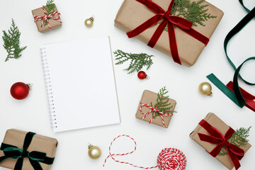 Mockup of white notebook surrounded by wrapped Christmas gifts and thuja branches in a festive setup