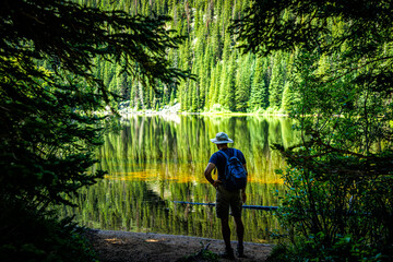 Beaver lake landscape hiking trail in Beaver Creek ski resort by Avon, Colorado water surface in summer in Holy Cross Wilderness, man standing looking