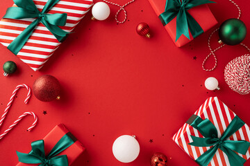 Christmas presents wrapped with ribbon surrounded by baubles and candy canes on a vibrant red backdrop for holiday cheer