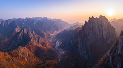 Fototapeta premium Majestic Mountain Landscape at Sunrise with River Flowing Through Autumn Forest and Rugged Peaks Under Soft Golden Light in Serene Natural Setting