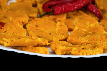 Selective Focus Of Gujarati Kathiyawadi Spicy Dhokali Sabji On White Plate, Red Chillies On The Top, Isolated On Black Background