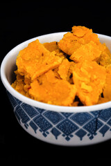 In a portrait orientation, the Gujarati Kathiyawadi Spicy Dhokali Sabji is elegantly displayed in a bowl, with a dramatic black backdrop that highlights its distinctive characteristics