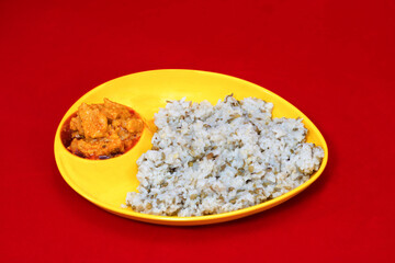 Close-Up view of Gujarati Kathiyawadi Spicy Dhokali Sabji with khichdi, on yellow dish prominently, set against a red background