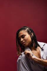 A young African American woman showcases her trendy braided hairstyle in a vibrant studio atmosphere.