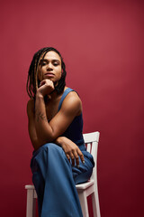Naklejka premium A young African American woman with braided hair strikes a confident pose against a vibrant backdrop.