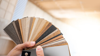 Designer hand picking sample of wood laminated material from natural collection. Customer choosing...