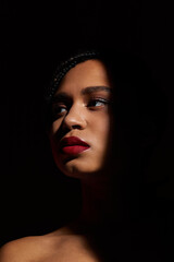 A young African American woman with braided hair and striking red lips showcases a confident pose in a studio.