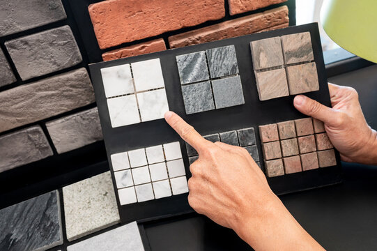 Architect hand pointing at stone tile collection display on sample board. Stone texture and pattern for architectural material ideas. Exterior or interior wall and floor finishing in natural style