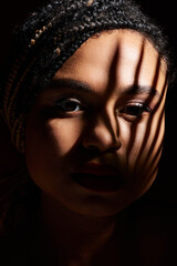 A young African American woman with braided hair and red lips showcases her style in a captivating studio atmosphere.