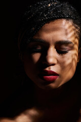 A young, fashionable woman with braided hair poses gracefully, showcasing her striking red lips in a studio setting.