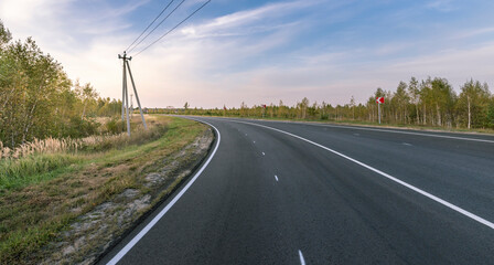 A long road with a red and white sign on the side