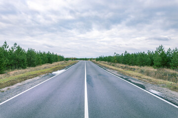 A long, empty road with a few trees in the background