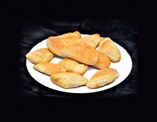ruddy pies on a white plate on a black velvet background