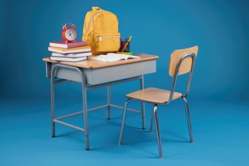 A school desk with a chair  a backpack  books  and an alarm clock.