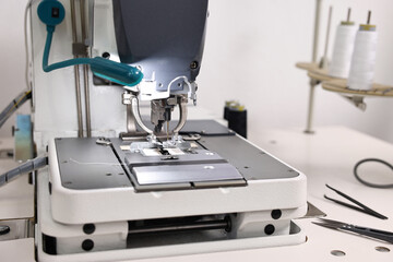 Sewing machine on white table in professional workshop, closeup