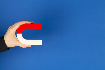 Woman with horseshoe magnet on blue background, closeup. Space for text
