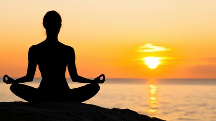 A person meditating on a cliff overlooking the ocean during a stunning sunset