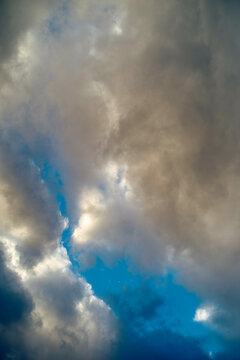 Sunlight breaking through dynamic blue and gray clouds in a dramatic sky.