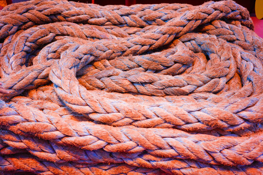 Twisted coils of thick brown rope in a heap on a cargo container ship.