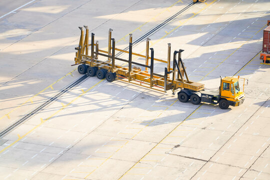 Aerial view of a terminal tractor towing a large empty cargo container chassis at a shipping port, Singapore
