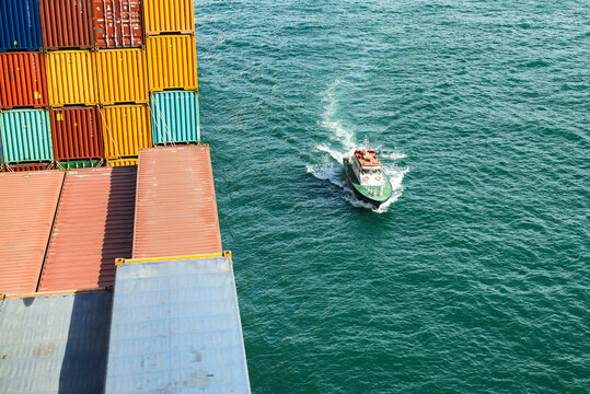 Aerial view of a large cargo ship transporting containers with a small pilot boat in the ocean, Singapore