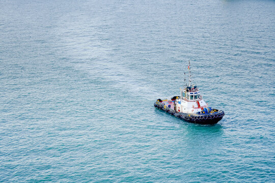 A tugboat sails on open blue waters under a clear sky, Singapore