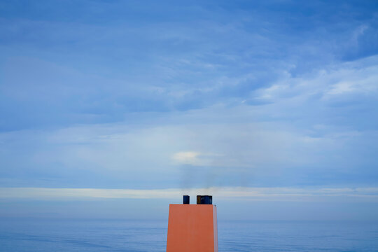 Smoke drifts from a ship's funnel against a backdrop of a calm sea and overcast sky, Busan, Korea