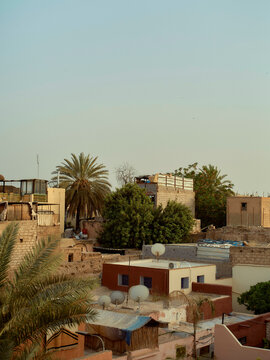 Sunset hues illuminate the traditional architecture and palm trees in a Middle Eastern urban landscape, Morocco