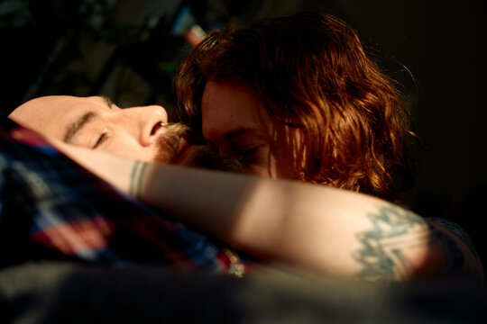 Intimate moment between a gay couple embracing in shadow and light.