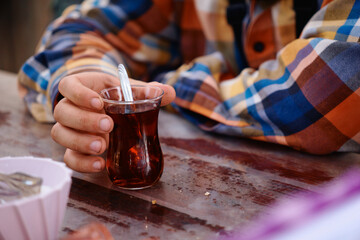 a man is sitting at a table and holding a glass Turkish glass with tea in his hands.