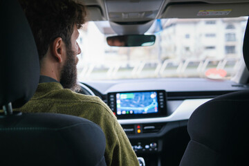 Man driving a car with a focus on the infotainment system and dashboard.