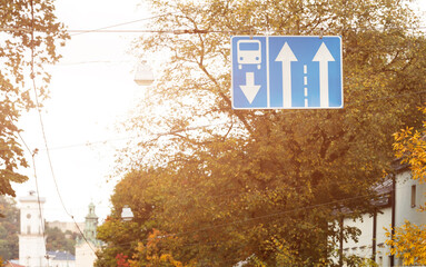 Fototapeta premium road sign above road vivid city scape view with Europe town background orange sun light