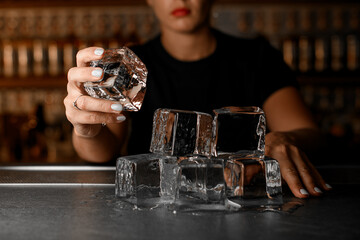 There are huge ice cubes on the bar counter that are slowly melting, one of which is held by a female bartender