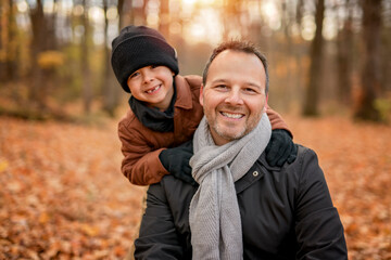 Fototapeta premium Joyful dad and his child boy. daddy and child have fun, laugh and enjoy nature outdoors at autumn park.