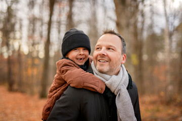 Fototapeta premium Joyful dad and his child boy. daddy and child have fun, laugh and enjoy nature outdoors at autumn park.