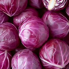 Fototapeta premium Fresh red cabbage heads are piled together, showing a vibrant purple color and interesting texture.