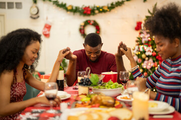 A family enjoys a festive Christmas dinner, sharing food and creating memories. A beautifully decorated Christmas tree and wreath add warmth, while candles and decor enhance the cozy holiday setting.