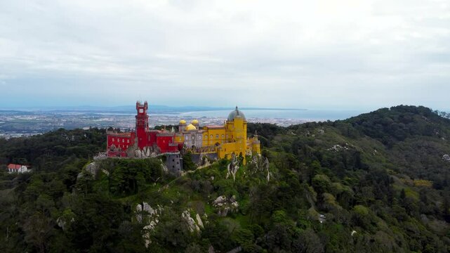National Palace of Pena Sintra, Portugal. Drone slowly ascending and camera tilt down. City of Sintra and Lisbon in background. Famous travel destination. The palace is a UNESCO World Heritage Site.