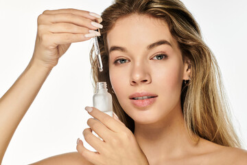 Fototapeta premium A young woman with radiant skin carefully applies a serum, embodying freshness and vitality.