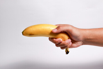 Male hand holding a ripe banana on isolated white background
