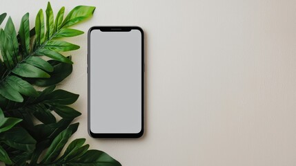 A blank smartphone rests beside lush green leaves on a textured surface, highlighting a blend of technology and nature.