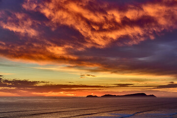 Obraz premium As the sun sets over San Lorenzo Island, the view from Miraflores becomes pure magic .The island silhouettes against a sky ablaze with color, while the ocean whispers of infinite horizons. 