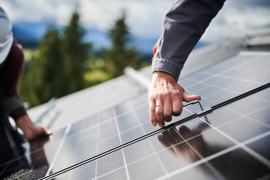 Professional workers securing solar cell on a roof. Close up view of installation of PV solar battery. Concept of green energy resources in modern life.