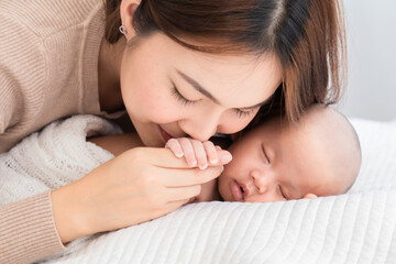 Asian beautiful mom motherhood lie down nursing, kissing newborn infant toddler, gently hold sleeping baby togetherin arm with love, infant sleep comfortably with safe and cuddle, mother taking care