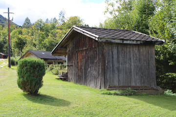 Vecchia baracca di legno nel borgo con prato siepe e cielo