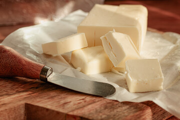 butter briquette, on wrapping paper, wooden chopping board and butter knife,breakfast, rustic style, no people,